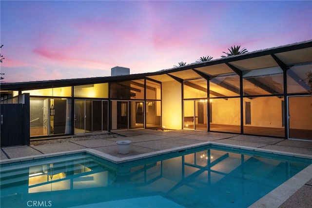 pool at dusk with a lanai and a patio