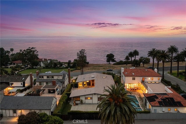 aerial view at dusk featuring a water view