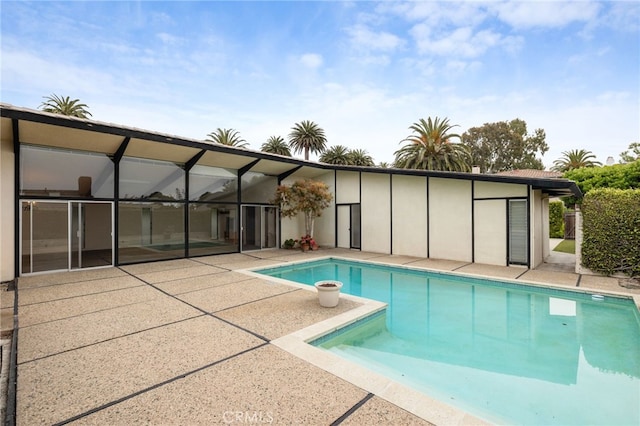 view of swimming pool featuring glass enclosure and a patio area