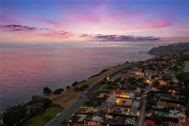 aerial view at dusk featuring a water view