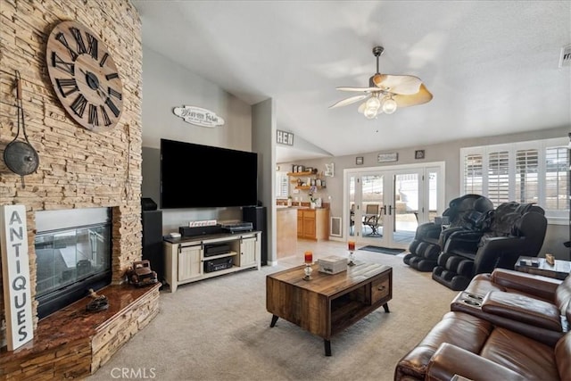 carpeted living room with ceiling fan, a fireplace, high vaulted ceiling, and french doors