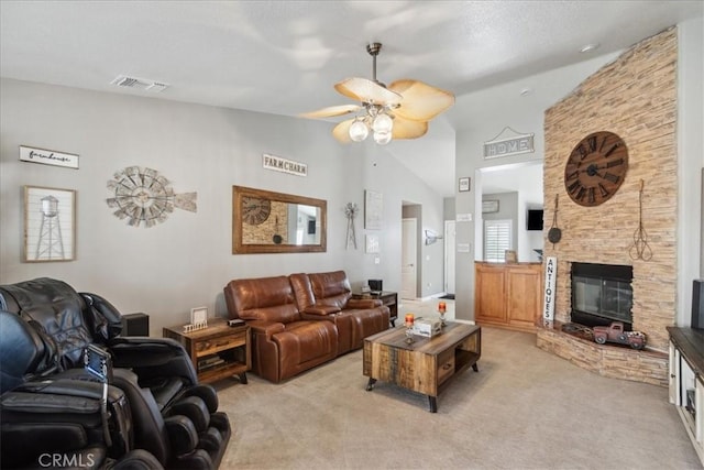 carpeted living room featuring a stone fireplace, ceiling fan, and high vaulted ceiling