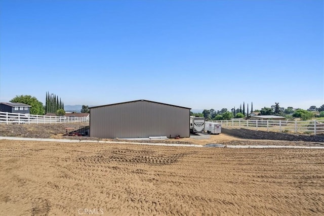 view of side of home featuring an outbuilding and a rural view