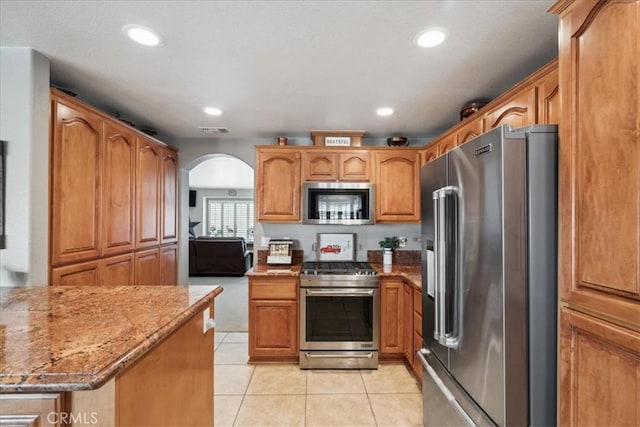 kitchen featuring light tile patterned flooring, high end appliances, and light stone counters