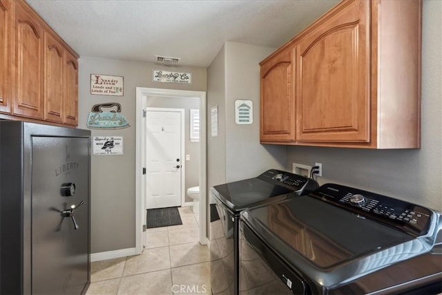 laundry room featuring cabinets, washing machine and dryer, and light tile patterned flooring