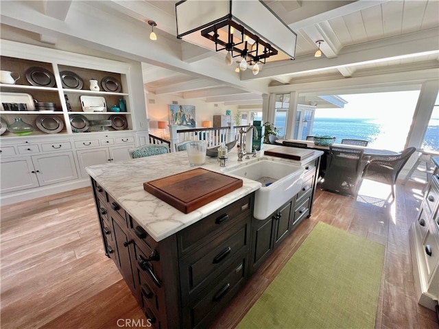 kitchen featuring sink, a center island, beamed ceiling, and light wood-type flooring