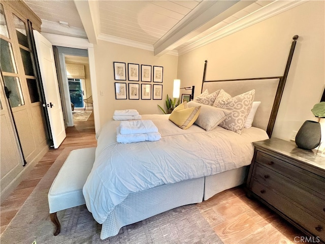 bedroom with light wood-type flooring, ornamental molding, and beam ceiling