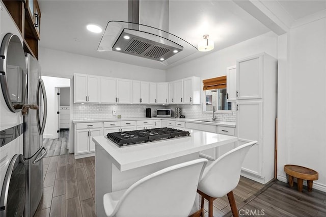 kitchen featuring a sink, decorative backsplash, stainless steel appliances, light countertops, and dark wood-type flooring