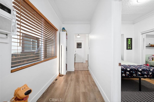 hall with baseboards, wood finished floors, crown molding, and a wall unit AC