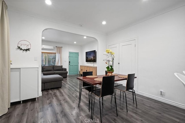 dining room featuring arched walkways, a wall unit AC, and dark wood finished floors