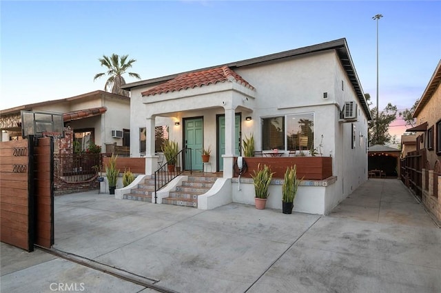 mediterranean / spanish-style house with a gate, fence, a tiled roof, and stucco siding
