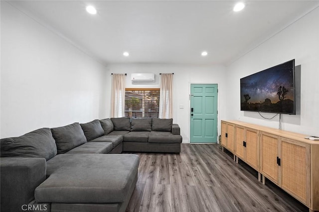 living area featuring wood finished floors, a wall mounted AC, and recessed lighting