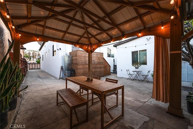 view of patio featuring fence, outdoor dining area, and a gazebo