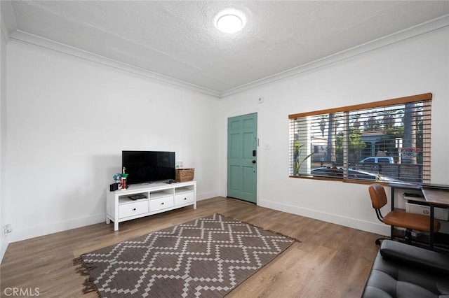 living area featuring baseboards, ornamental molding, wood finished floors, and a textured ceiling