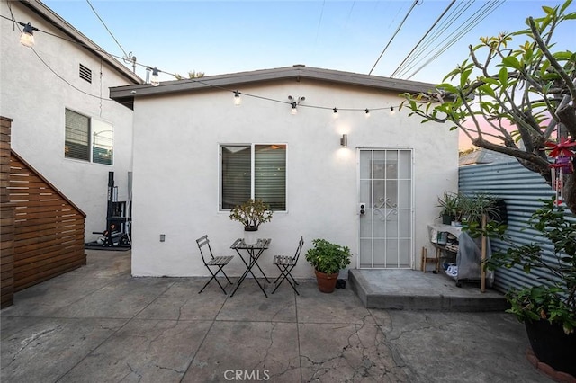 rear view of house featuring a patio area and stucco siding