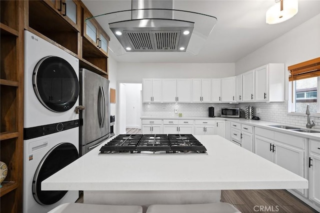 kitchen featuring a breakfast bar, stainless steel appliances, stacked washing maching and dryer, and a sink