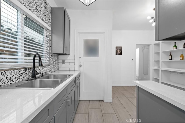 kitchen featuring light countertops, gray cabinetry, and a sink