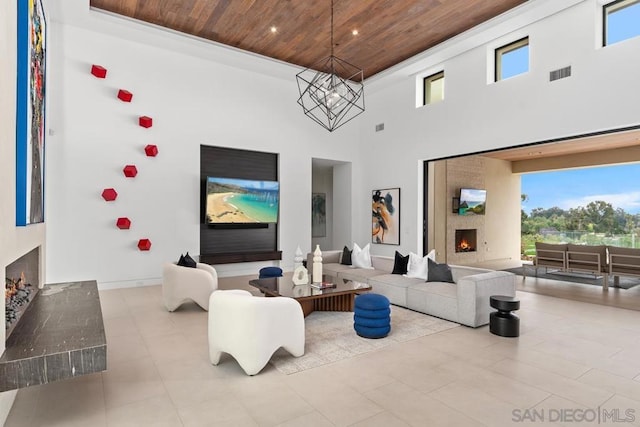 living room with a wealth of natural light, wood ceiling, a high ceiling, and an inviting chandelier