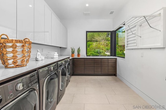 laundry room featuring cabinets, separate washer and dryer, sink, and light tile patterned floors