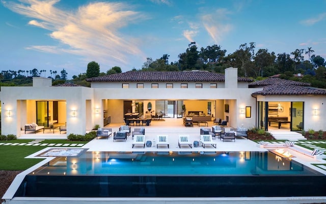 back house at dusk featuring an outdoor hangout area and a patio