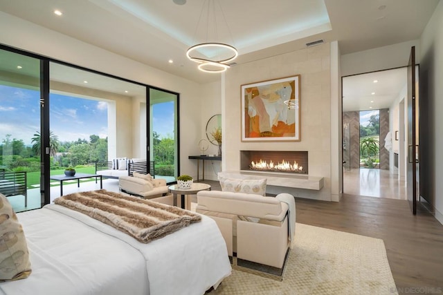 bedroom with a raised ceiling, access to exterior, and wood-type flooring