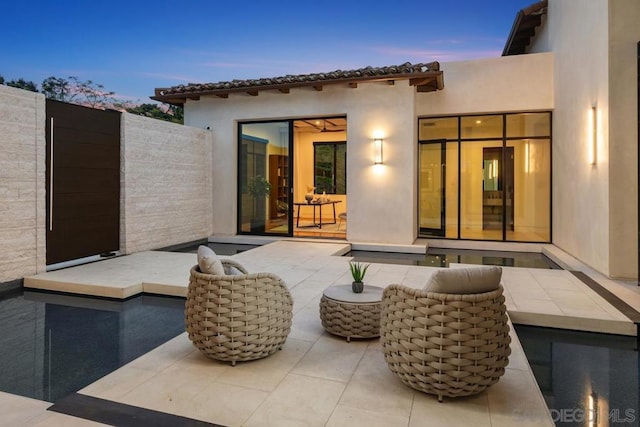 back house at dusk featuring a patio area