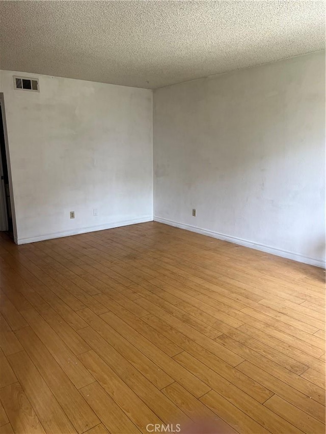 unfurnished room with a textured ceiling and light wood-type flooring