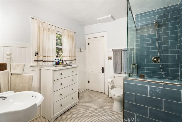 bathroom featuring tile patterned flooring, toilet, and a shower with door