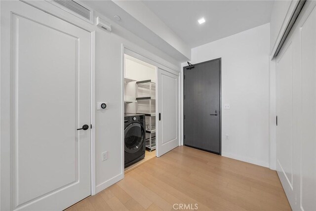 laundry room with washer / dryer and light wood-type flooring