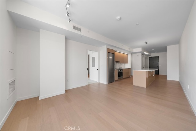 unfurnished living room featuring track lighting and light hardwood / wood-style floors