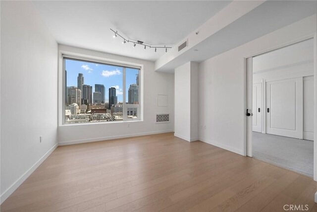 unfurnished room featuring light hardwood / wood-style floors and rail lighting