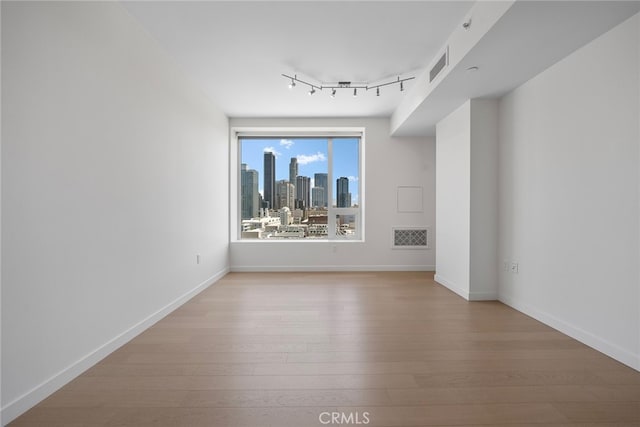 spare room featuring hardwood / wood-style floors and track lighting