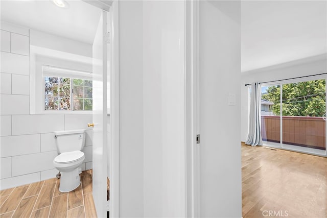 bathroom featuring hardwood / wood-style floors, tile walls, and toilet