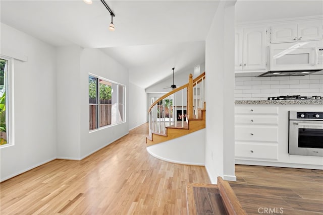 kitchen with white cabinetry, light hardwood / wood-style flooring, gas stovetop, backsplash, and stainless steel oven