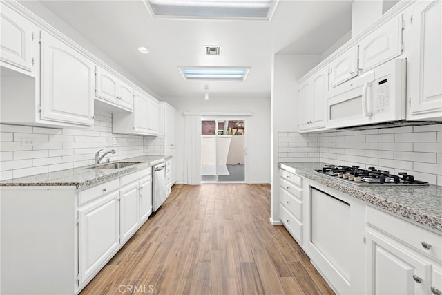 kitchen with light hardwood / wood-style flooring, stainless steel appliances, backsplash, white cabinetry, and sink