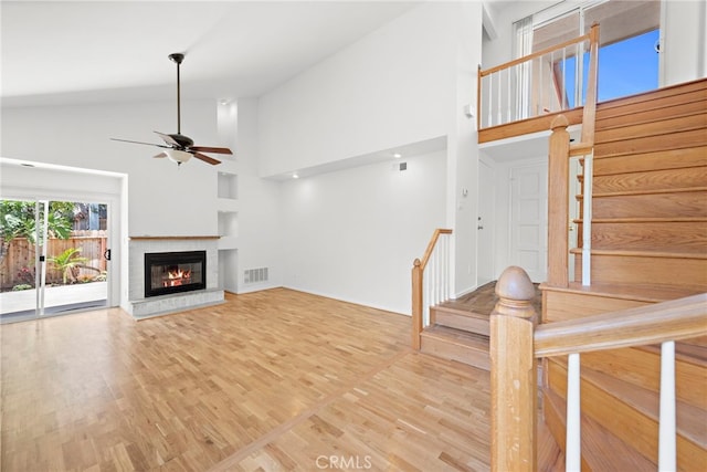 unfurnished living room featuring high vaulted ceiling, ceiling fan, and light wood-type flooring