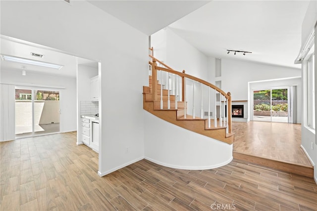 1585 Catalina, Laguna Beach, CA 92651 - staircase with healthy amount of natural light, wood finished floors, a warm lit fireplace, rail lighting, and high vaulted ceiling