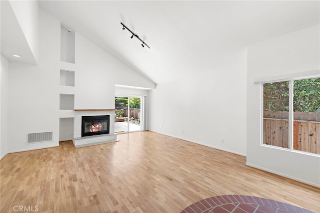 1585 Catalina, Laguna Beach, CA 92651 - unfurnished living room with track lighting, wood finished floors, a glass covered fireplace, high vaulted ceiling, and baseboards