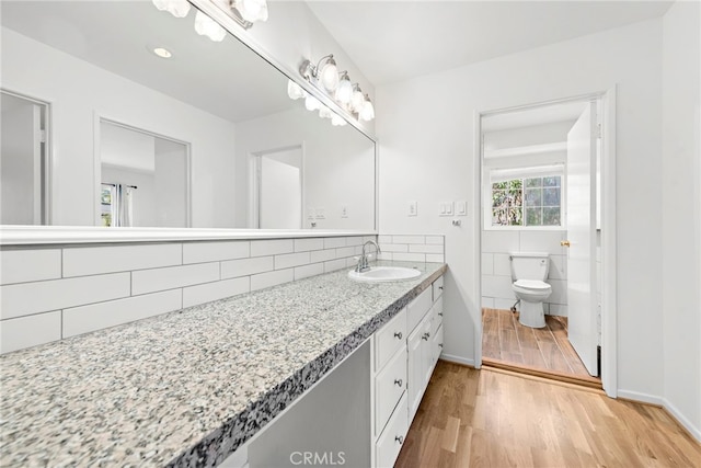 bathroom with tile walls, hardwood / wood-style flooring, large vanity, and toilet