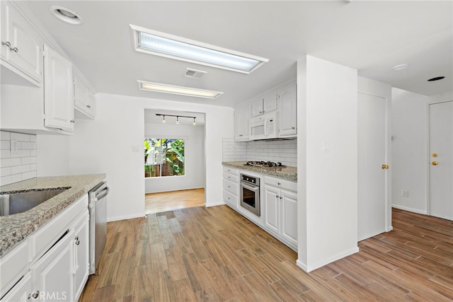 kitchen featuring appliances with stainless steel finishes, white cabinetry, tasteful backsplash, and light hardwood / wood-style flooring