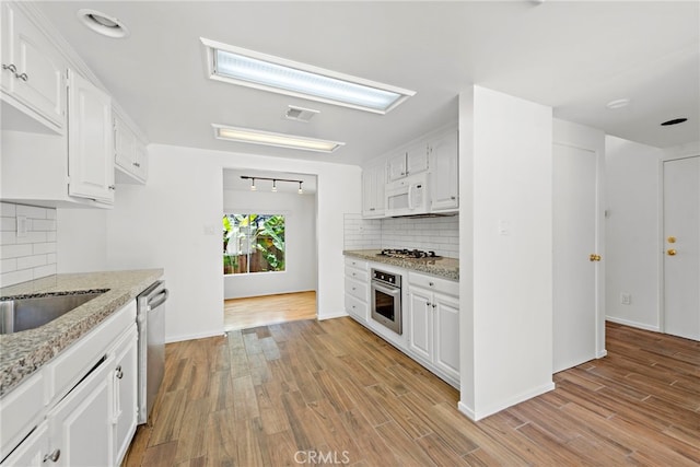 1585 Catalina, Laguna Beach, CA 92651 - kitchen featuring appliances with stainless steel finishes, backsplash, light stone counters, and light wood finished floors