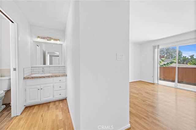 bathroom with hardwood / wood-style flooring, tasteful backsplash, vanity, and toilet