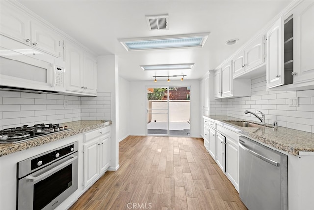 kitchen with stainless steel appliances, light hardwood / wood-style floors, white cabinetry, and tasteful backsplash