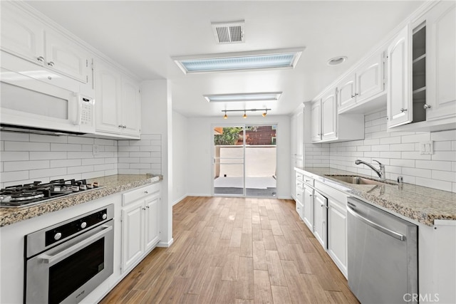 1585 Catalina, Laguna Beach, CA 92651 - kitchen with appliances with stainless steel finishes, a sink, white cabinetry, tasteful backsplash, and light stone countertops