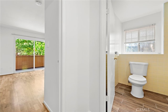 bathroom featuring wood-type flooring, plenty of natural light, tile walls, and toilet