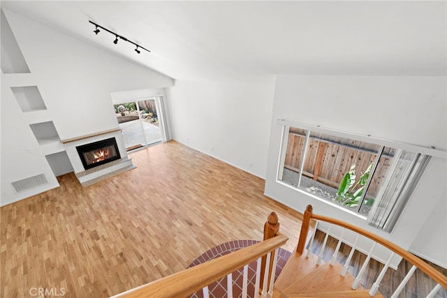 living room with light hardwood / wood-style floors, track lighting, and vaulted ceiling