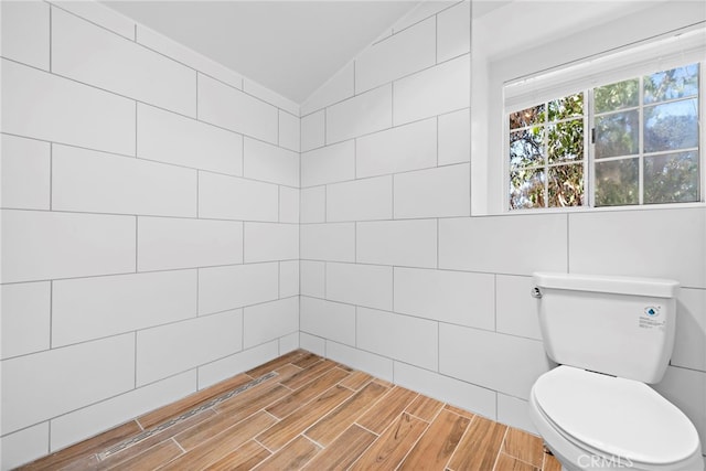 bathroom featuring tile walls, lofted ceiling, and toilet