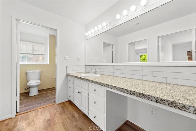 bathroom with tile walls, backsplash, vanity with extensive cabinet space, toilet, and hardwood / wood-style floors