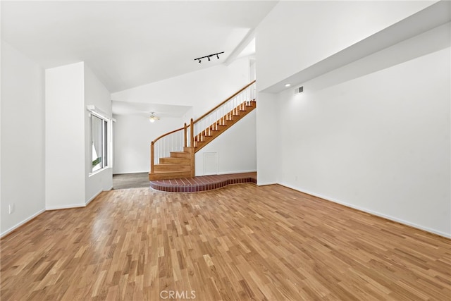 unfurnished living room featuring high vaulted ceiling, light hardwood / wood-style flooring, and track lighting