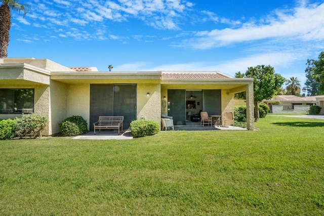 rear view of house featuring a lawn and a patio